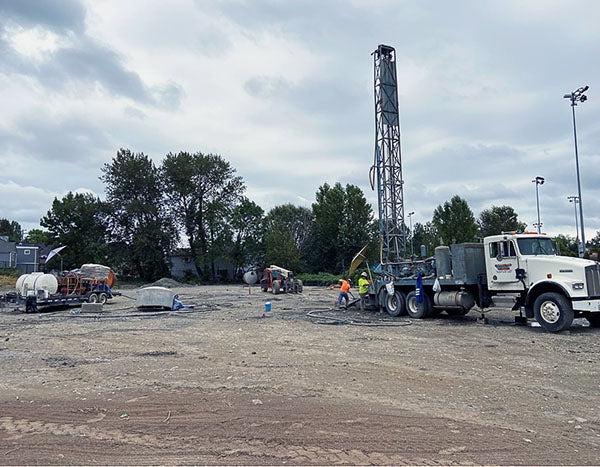 a truck with a tall drill attached and people working